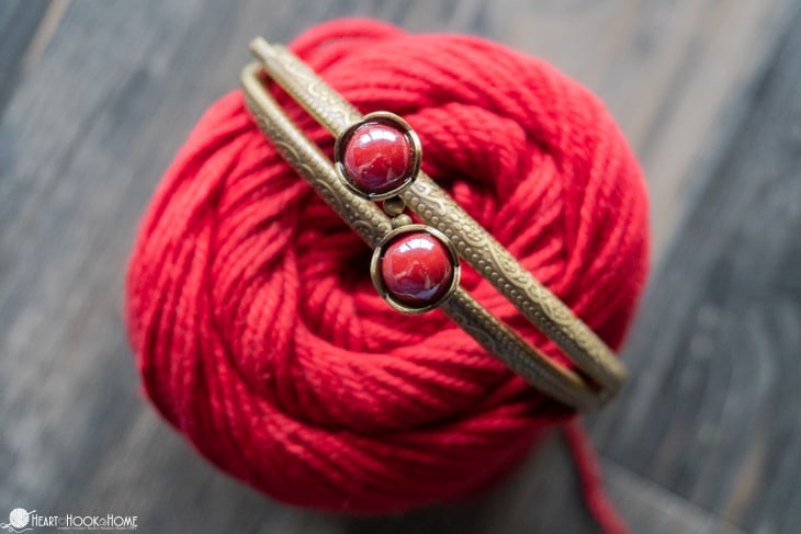 Kiss Coin Purse Clasp on top of a skein of rose colored Knit Picks Dishie cotton yarn.