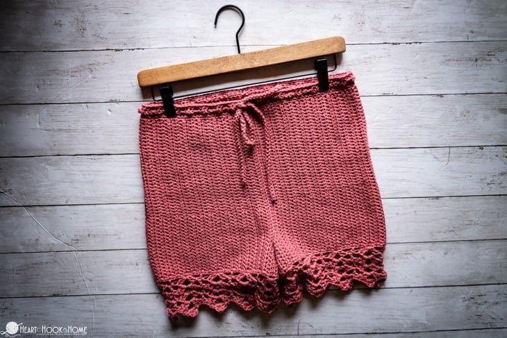 Peony colorway of the Staycation Shorts crochet pattern on a wooden hanger.